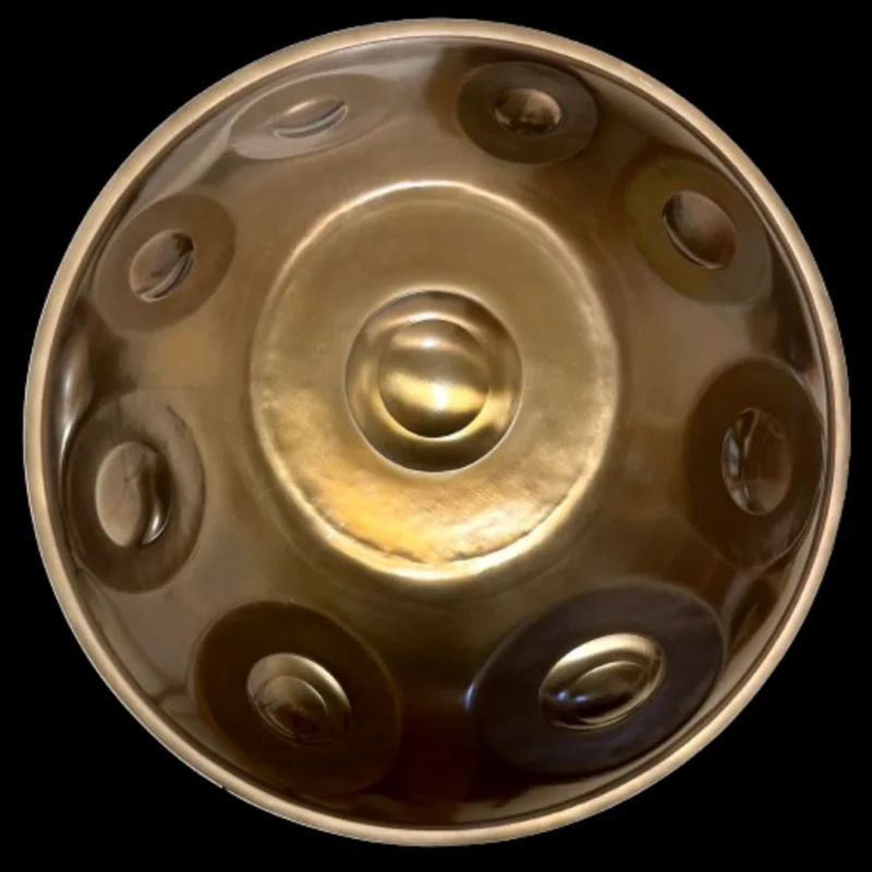 Handpan Yishama F2 Astronaut vu de dessus sur fond noir : surface dorée brillante, le ding au centre et une douzaine de zones de notes visibles.